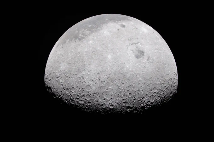 The Moon appears half-illuminated in this photo captured by the Artemis II crew on April 6, 2026. The terminator — the difference between light and darkness — provides a stark contrast and even greater perspective of the Moon's rocky, uneven, and otherworldly surface features. The near side of the Moon, which is what we can see from Earth, appears in the dark gray regions at the top of this image. The Moon stands out against the blackness of space around it. Credit: NASA
