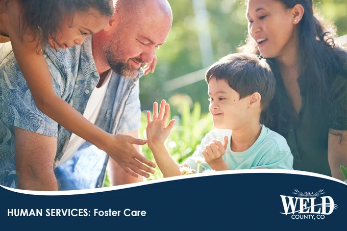 A diverse family warmly interacting outdoors, with a young boy giving a high-five to a man, symbolizing foster care support.