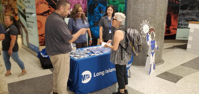 A group of people around an informational table in Grand Central Madison. 