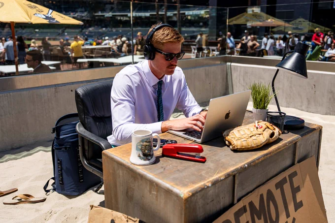 Photo of Scott Muirhead sitting at his desk in the sandbox in Gallagher Square. He has headphones on and is working at his laptop for Remote Work Wednesdays.