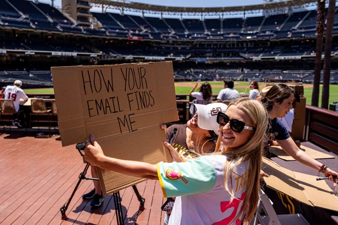 Photo of a Padres fan holding up a sign that says "How Your Email Finds Me" in Gallagher Square.