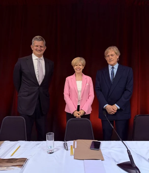 Three people posing for a photo in front of a table with a mic 