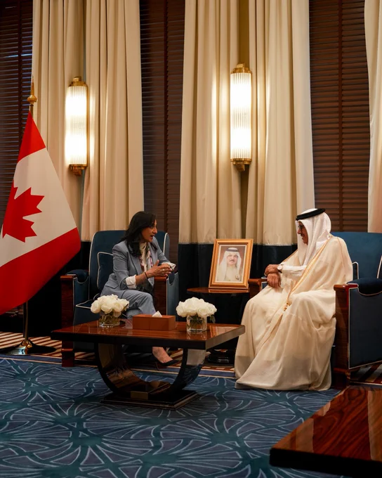 Minister Anand (on the left) seated during a meeting with His Excellency Dr. Abdullatif bin Rashid Al Zayani, Minister of Foreign Affairs of the Kingdom of Bahrain (on the right), with a Canadian flag in the background.