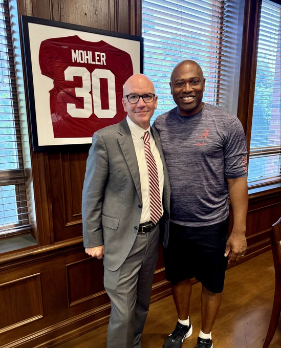 President Mohler standing next to Shaun Alexander in front of an Alabama jersey that says Mohler 30.