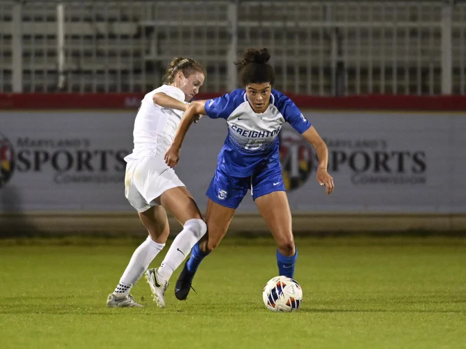 Two soccer players from are competing for the ball during a nighttime match.