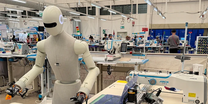 A humanoid robot working alongside employees at a garment manufacturer.