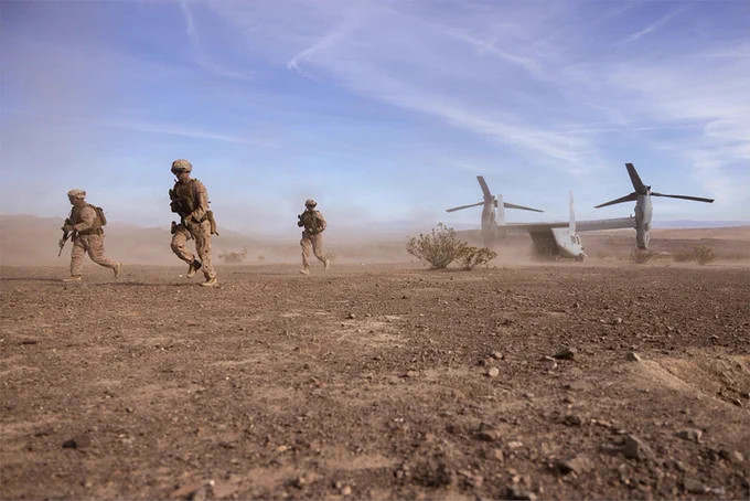 Marines move away from a MV-22 Osprey after landing in a desert training area during a recovery mission exercise.
