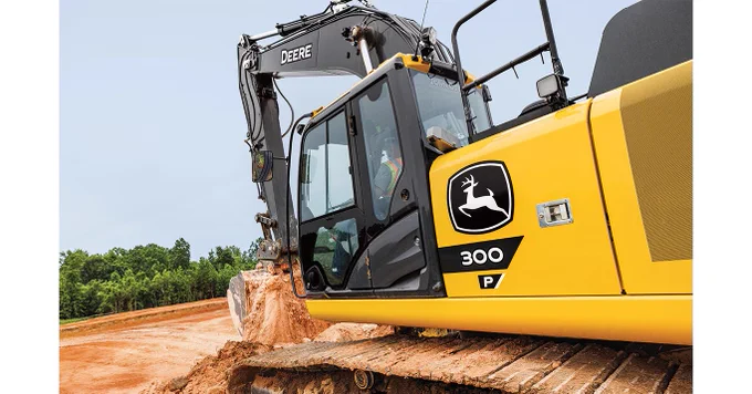 A yellow John Deere excavator, labeled "300 P," is actively digging in a dirt area, surrounded by trees in the background.
