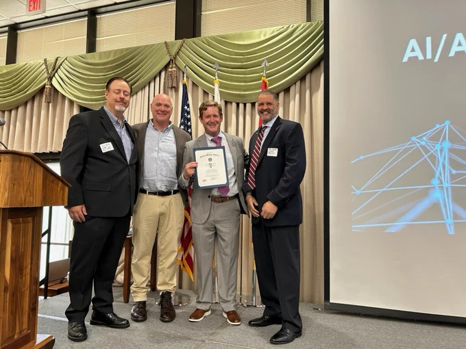 Pictured on stage presenting a certificate to SBA Regional Administrator Matt Coleman at the SAME New Jersey AI/Automation Day at Joint Base McGuire-Dix-Lakehurst are (l to r) U.S. Air Force's Small Business Programs Procurement Analyst and Small Business Professional James Burke, SBA New Jersey District Director John Blackstock, SBA Regional Administrator Matt Coleman, and Society of Military Engineers New Jersey Chapter President Robert Jackson of GZA GeoEnvironmental.