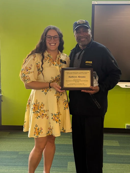 Katie Abrams stands with UI REACH Director Bill Lloyd, holding the award.