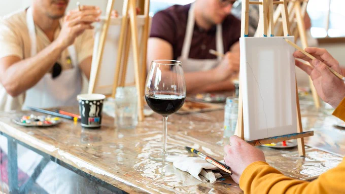 Adults create works of art on a blank canvas sitting on an easel during a Paint and Sip class.