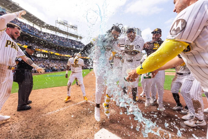 Photo of Fernando Tatis Jr. running/jumping near home plate after hitting a walk-off home run. His teammates are surrounding him and there's blue Gatorade being poured on him.