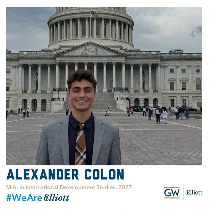 Alex Colon smiles standing in front of the US Capitol building wearing a suit and tie