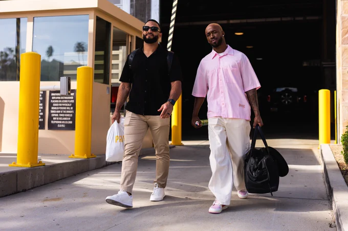 Photo of Rodolfo Durán and Samad Taylor exiting Petco Park for the road trip. They are both looking at the camera as they walk towards the team bus.