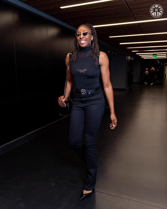 Nneka wearing black jeans and black mesh tank with Black pumps.