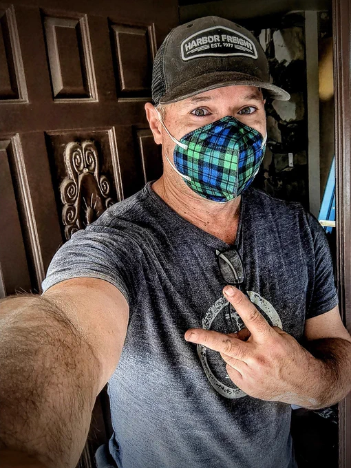 At work, Patrick is wearing a plaid KN95 respirator, a Harbor Freight truck cap, made a peace sign for a selfie.