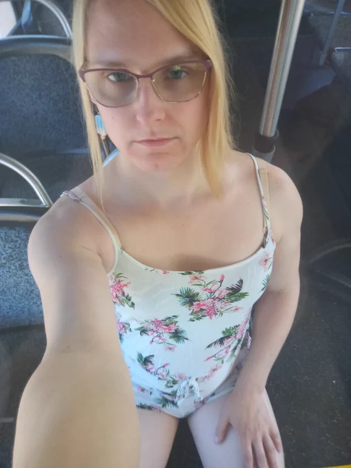 Woman in a cami string top floral romper sitting in a bus.

She looks relaxed.