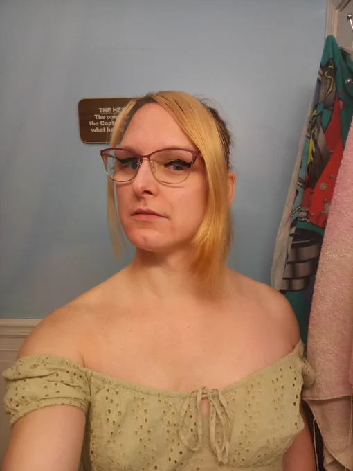 A woman with long blonde curtain bangs in a light and airy green puffy sleeve top.

She's giving a sultry RBF looking down at the camera at an angle.