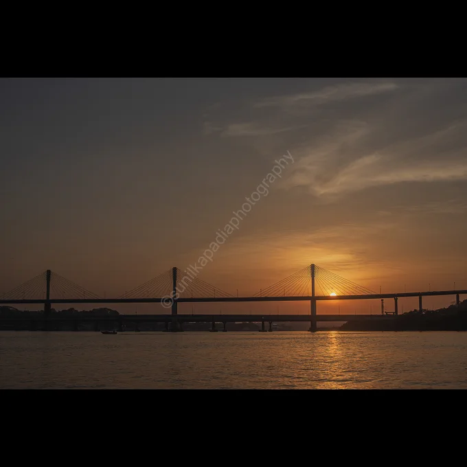 A color image of a landscape in the form of a riverscape with the name of the river as Mandovi. The road bridge across the river is an architecture splendour and the sunset makes the landscape very attractive, splendiferous and serene. Goa, India
I shot this image to depict the serenity during sunset over the Mandovi river in Goa with a wonderfully architectured bridge going across it. 
To purchase this photo art print, please message me directly here for more specifications and details.