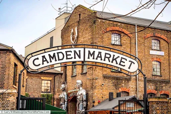 The Camden Market sign over the Chalk farm entrance in front of the old industrial brick buildings.

