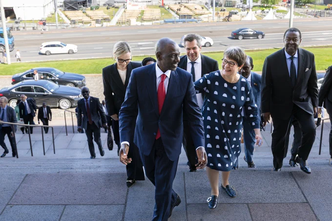 Kenian presidentti William Ruto vieraili eduskunnassa 10. kesäkuuta 2026 ja tapasi toisen varapuhemiehen Tarja Filatovin sekä eduskuntaryhmien johtoa. Kuvassa presidentti ja varapuhemies nousevat Eduskuntatalon portaita ja katsovat toisiinsa hymyillen. Taustalla delegaatioiden jäseniä ja kesäinen Mannerheimintie autoineen. 