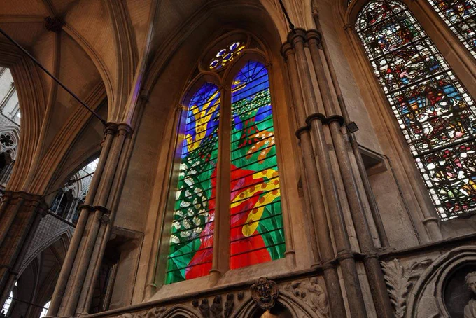 The completed Queen's Window - a large, colourful stained glass window depicting an abstract countryside scene - in Westminster Abbey