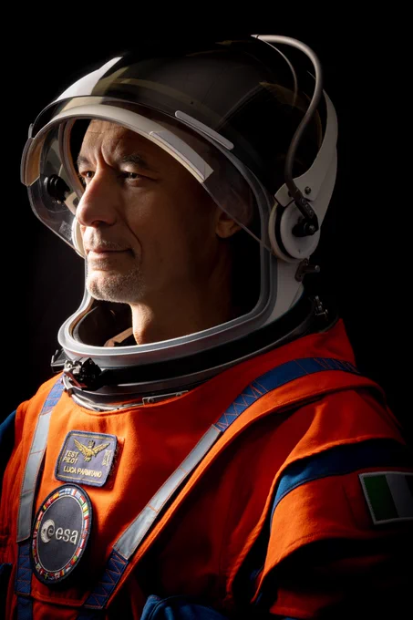ESA astronaut Luca Parmitano in his orange Artemis flight suit, with an ESA patch, against a black background. Credit: NASA