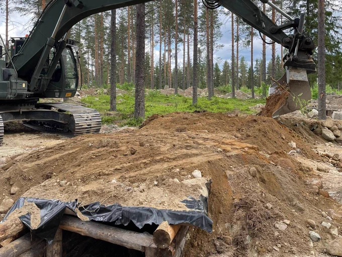 varusmiehet rakentavat juoksuhautaa maastossa kaivinkoneella
