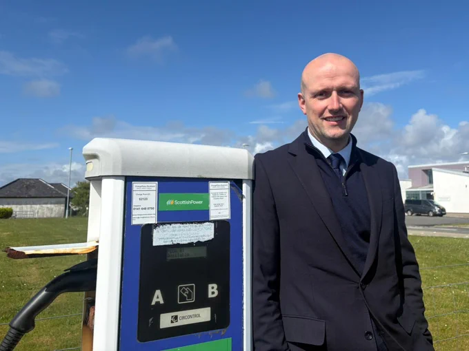 Transport Secretary Stephen Flynn poses for a photo next to a public charge point on South Uist.