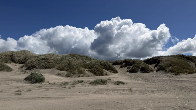 Blick über den Strand zu den Dünen mit tollen Wolken.