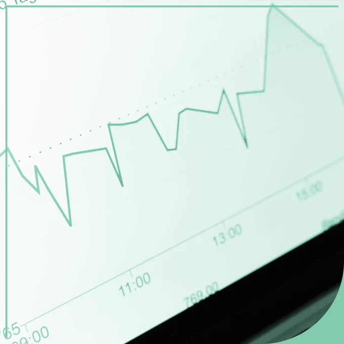 A close-up photograph of a digital graph displayed on a screen. A green line representing data rises and falls throughout the day, with several sharp dips and peaks, but follows an overall upward trend. Time markers along the bottom of the graph show intervals including 11:00, 13:00, and 15:00. The image has a soft teal overlay and a modern, data-driven aesthetic, symbolising the analysis and visualisation of changing information over time.