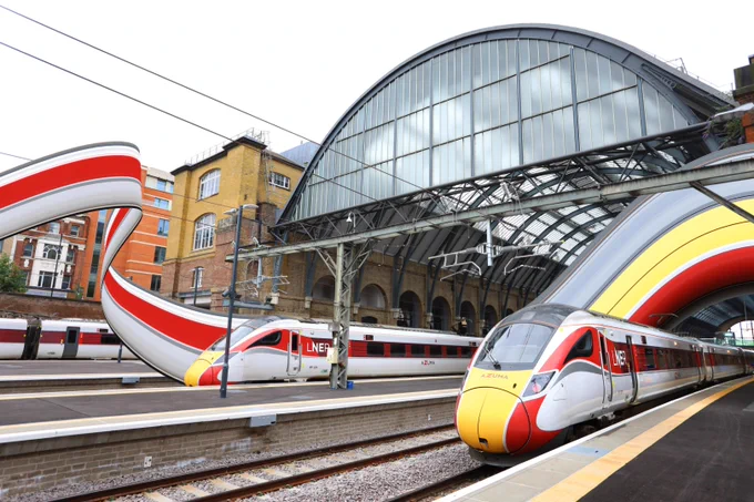Two Azuma trains in King's Cross with slices of their livery colours stretched and twirling away from them.