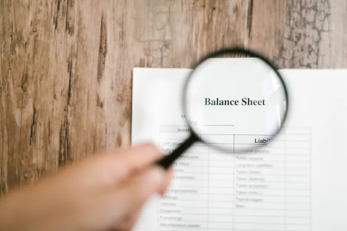 visual photograph with a sheet of paper under a magnifier highlighting the words 'Balance Sheet' to denote company accounts and finance