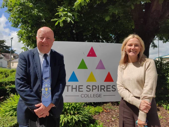 Steve and Alex Newton in front of the sign for The Spires College 
