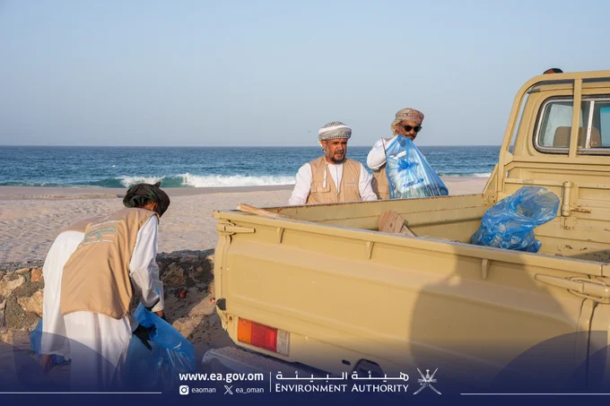 صورة لأشخاص يجمعون النفايات ويضعونها على المركبة.
