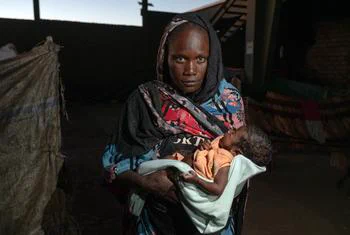 ©UNOCHA/Giles Clarke A woman holds her malnourished child at a displaced site in Gedaref, Sudan.