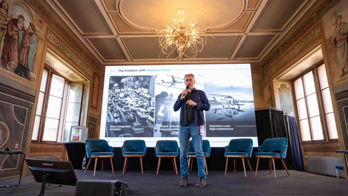 Zuri founder Michal Illich on stage at Innovations United 2026, Prague Castle, presenting a slide titled The Problem with Regional Travel.