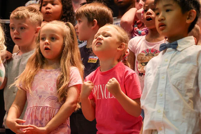 Students sings and holds hands in fists on stage