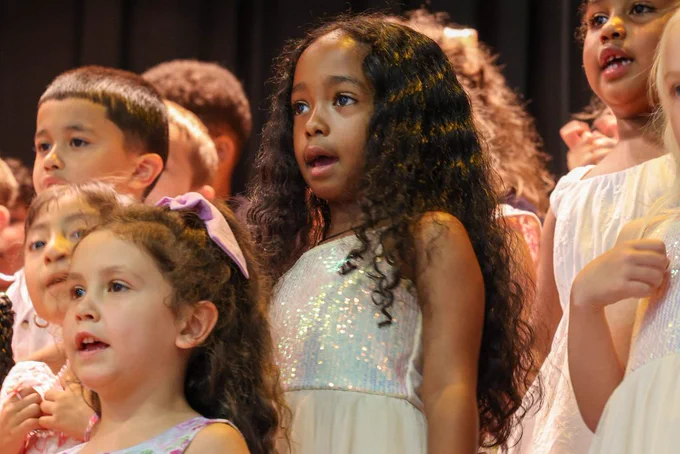 student sings in a white glitter dress on stage