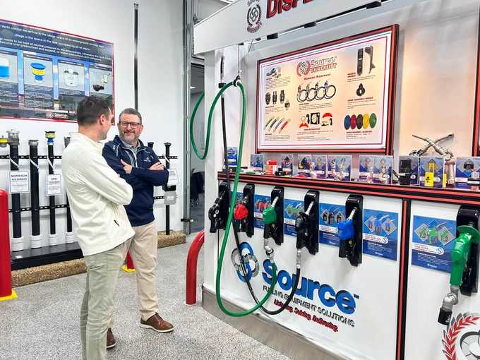Two people stand in front of a display of fuel dispenser nozzles at the Source University training center in Texas. 