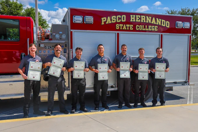 Cadets posing with their certificates in front of the PHSC firetruck after ceremony.