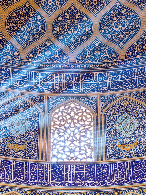 Architectural study from Sheikh Lotfollah Mosque highlighting a narrow beam of filtered light cutting through patterned tilework and calligraphy.