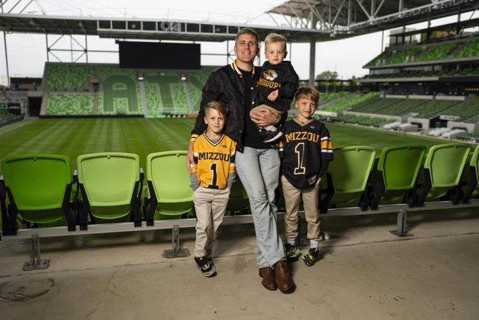 Ryan Madden poses in a soccer stadium with his sons.