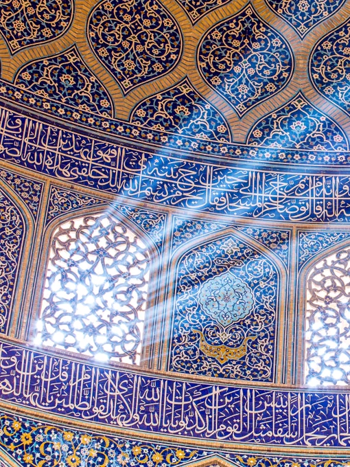 Architectural study from Sheikh Lotfollah Mosque highlighting a narrow beam of filtered light cutting through patterned tilework and calligraphy.