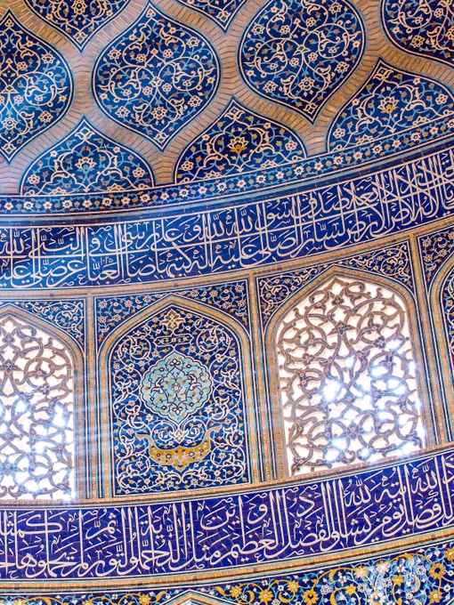 Architectural study from Sheikh Lotfollah Mosque highlighting a narrow beam of filtered light cutting through patterned tilework and calligraphy.