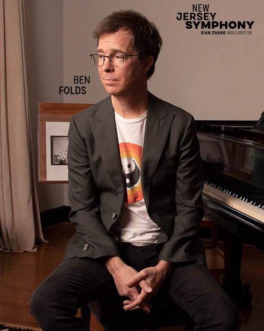 Headshot of Ben Folds sitting next to a piano.