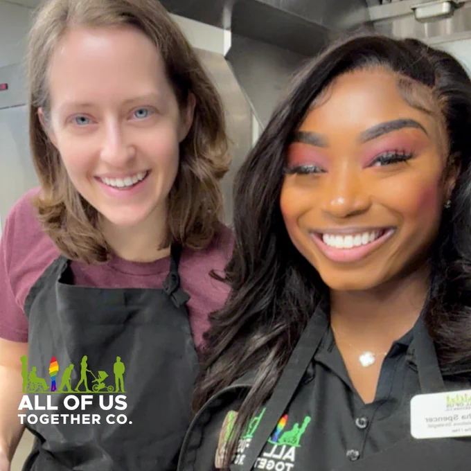 A selfie like image featuring two (2) smiling, standing women when cooking aprons on. Company logo positioned left in footer.
