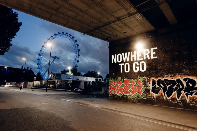The words 'NOWHERE TO GO' are projected under a bridge with the London Eye in the background.