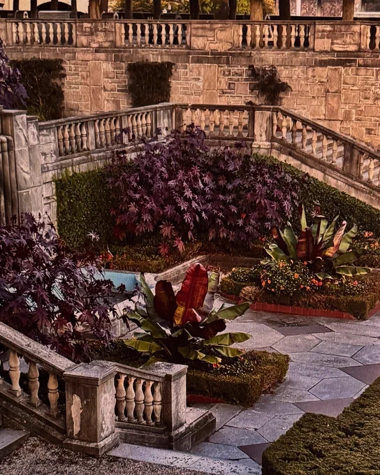 A beautifully landscaped garden with stone balustrades and stairs, featuring lush purple and green plants. The garden has a classical architectural style with neatly trimmed hedges and a stone walkway.