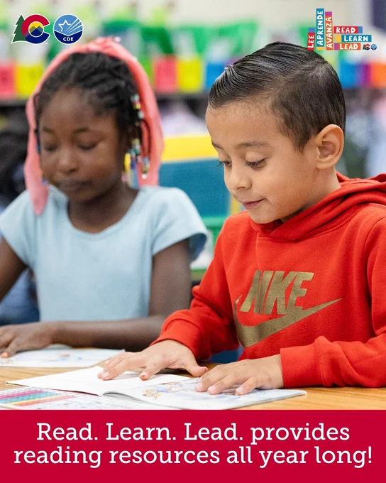 Two children are sitting at a table in a classroom, reading books. The child on the left is wearing a blue shirt with pink hair accessories. The child on the right is wearing a red Nike hoodie. A banner reads, "Read. Learn. Lead. provides reading resources all year long!"